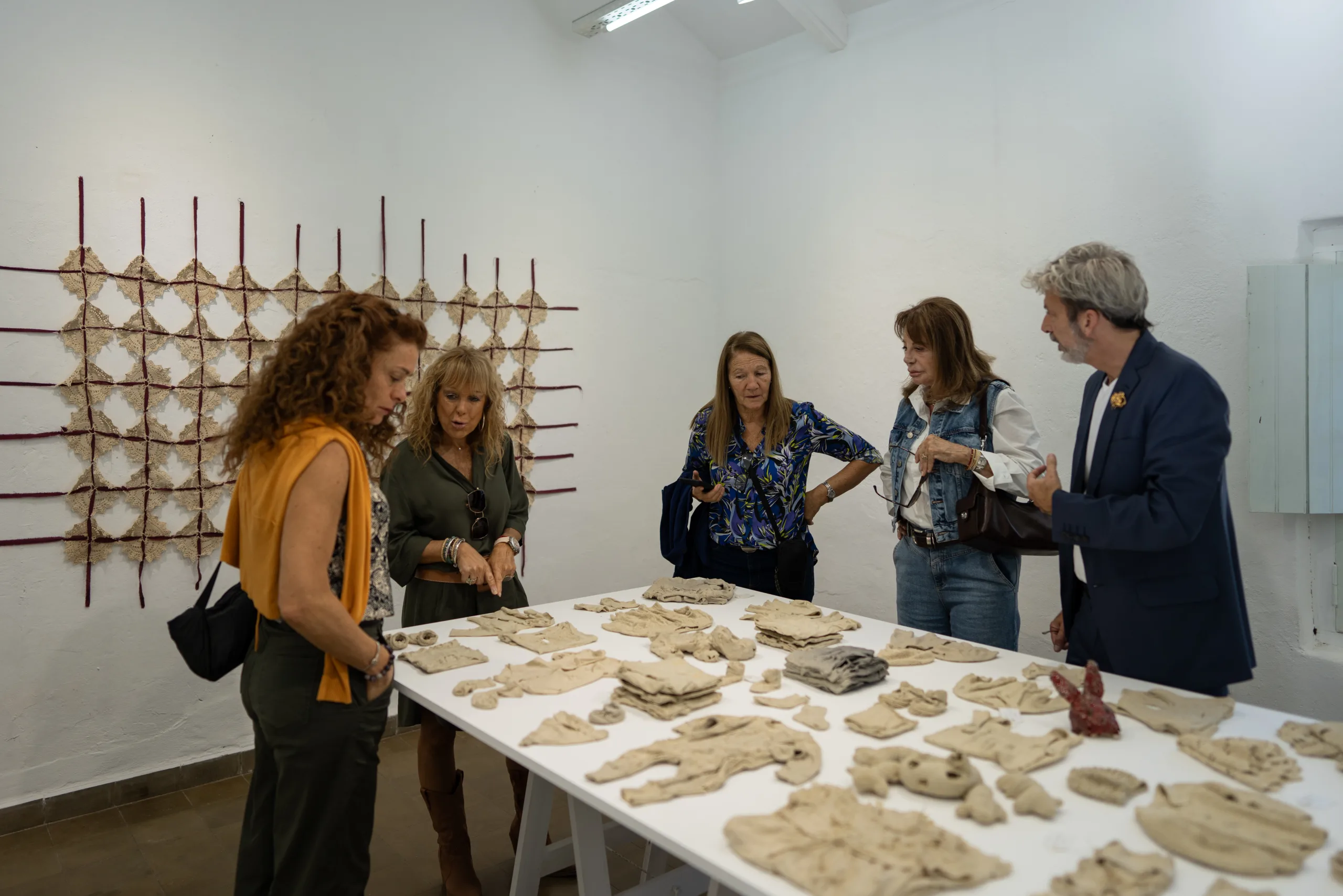 Varias personas miran piezas de cerámica sobre una mesa