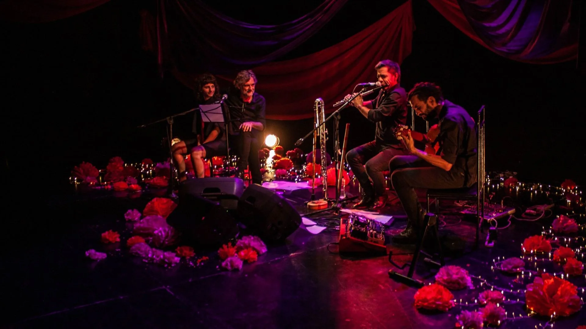 Cuatro personas en escena, leyendo poesía y tocando música