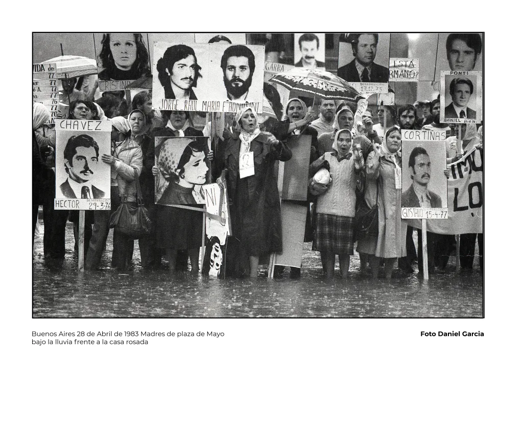 Madres de plaza de mayo sostienen pancartas con nombres y fotos de sus hijos desaparecidos bajo la lluvia