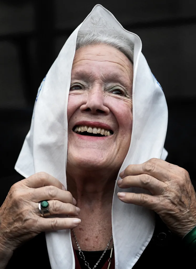 Nora Cortiñas sonrie mientras se coloca sobre la cabeza el pañuelo que identifica a las Madres de Plaza de Mayo