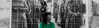 Una mujer vestida de verde delante de una foto en blanco y negro