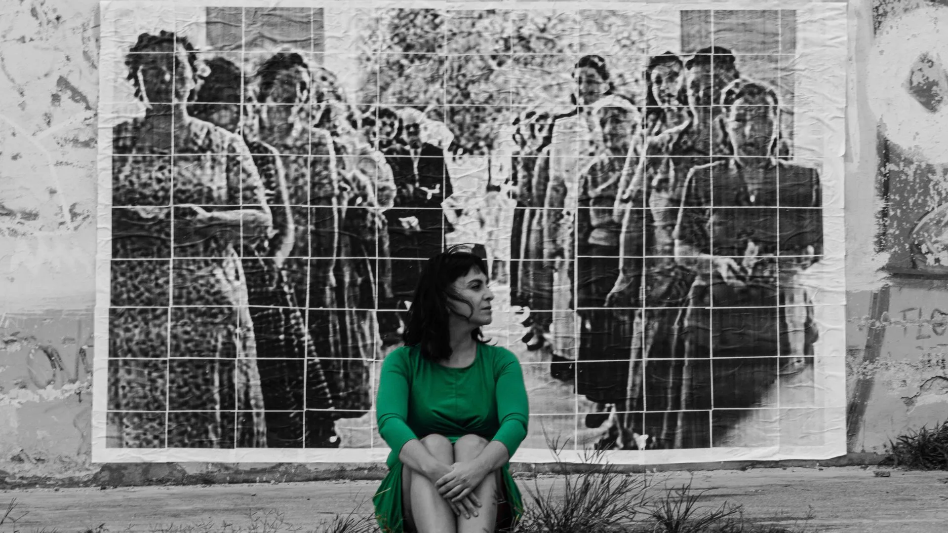 Una mujer vestida de verde delante de una foto en blanco y negro